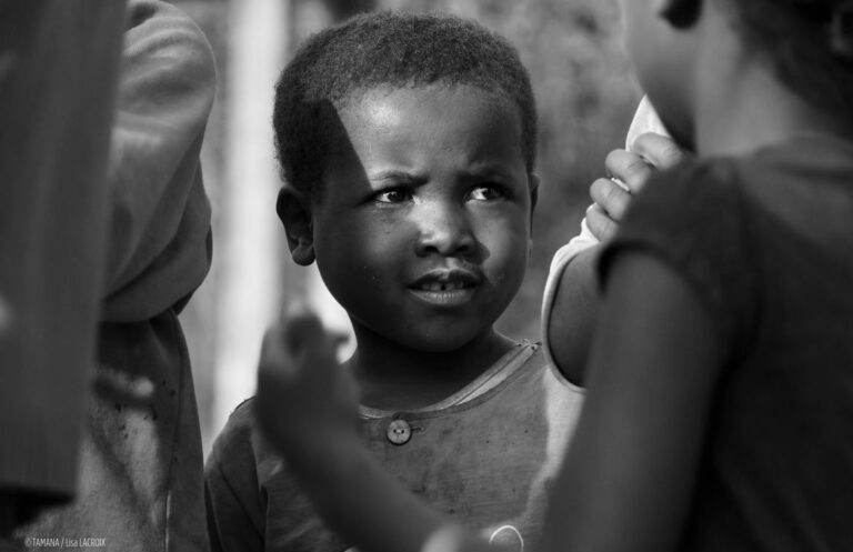 Photo en noir et blanc d’un petit garçon malgache souriant.